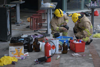 消防員整理大量疑危險品，當中包括懷疑汽油彈、易燃氣體及液體、玻璃樽及食油等。