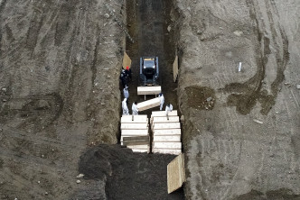 多名穿上防護衣的人員在島上挖坑埋葬屍體。AP