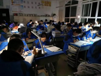 四川一所中学学生停电下自备枱灯继续温习。网图