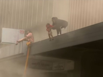 一名南非母親準備從失火大樓拋下孩子。