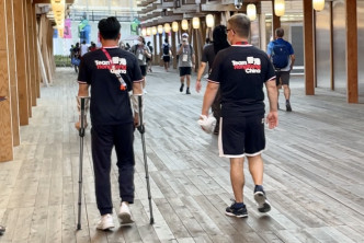 石伟雄（左）左脚受伤，要扶着拐杖走路。  梁柏琛摄