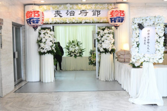 灵堂以白色鲜花为主入口摆放著米白色帘幕。