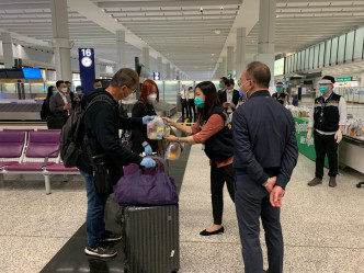 入境处人员在香港机场为乘坐包机的港人送上由航空公司提供的食物包。