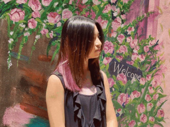 Celine頭髮內層染了粉紅色，站在戶外壁畫展示側面。IG圖片