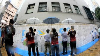 壁画涂色活动进行期间一度下雨，一批西区警务人员贴心地为参与者打伞，并让参与的小孩穿上雨衣。