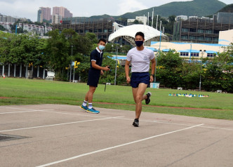  督察羅錦峯(右)示範八百米跑測試。 林家希攝