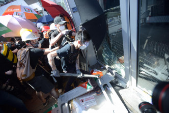示威者以硬物衝擊玻璃門。