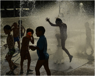 西班牙有小童在路邊玩水降溫。 AP