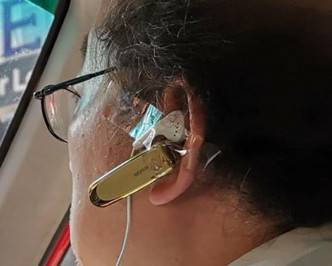 左耳戴著一個免提耳機，更用膠紙將一個連接電話的有線耳筒貼在左耳上。網民GeorGe Wong‎圖片