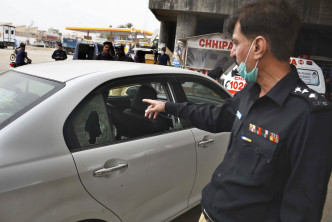 巴基斯坦卡拉奇一条公路上，两名摩托车枪手向一辆属于中国公民的车辆开火，一名警察在现场调查。美联社图片