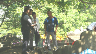 右面蓝衣男子苏先生发现母亲坟墓被毁。
