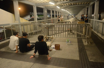 凌晨时分，数名示威在坐于中信大厦天桥上的铁马前。