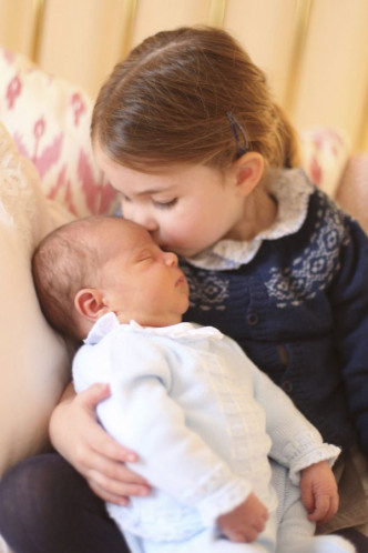 姊姊夏洛特公主用手抱著路易王子轻吻他的前额，十分温馨。AP