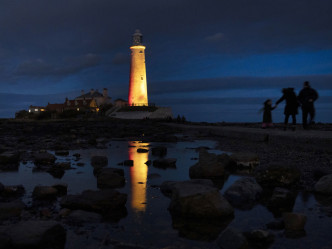 在英格蘭的惠特利灣，聖瑪麗燈塔亮燈紀念抗疫一周年。AP圖片