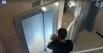 男邻居抱著狗狗在升降机门前，等候女子接回狗狗。 Youtube 截图