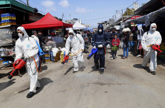伊朗工人在市場噴灑消毒劑。 AP