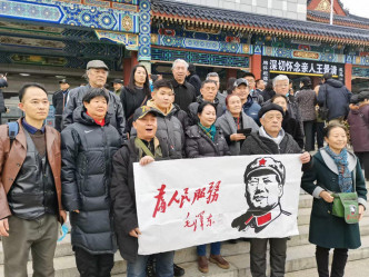 有民众展示毛泽东「为人民服务」的横幅。