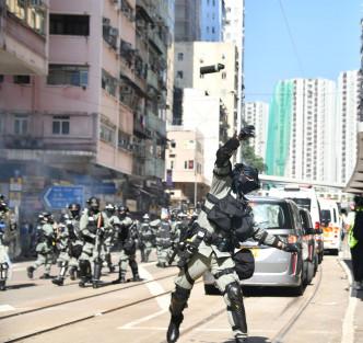 防暴警员冲出，在筲箕湾道举黑旗和发射催泪弹。