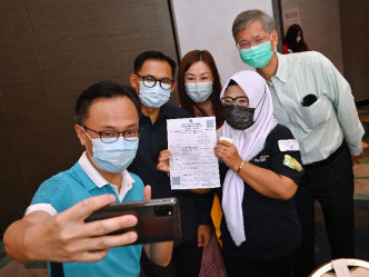 聂德权（左一）、罗致光（右一）、李吉（左二）与一名完成接种疫苗的印尼人士自拍留念。政府新闻处图片