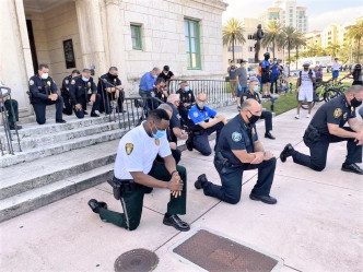 佛州科勒尔盖布尔斯市有警员单膝下跪悼念死者。网图