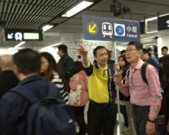 金钟站工作人员指示乘客如何由荃湾线月台到下层转乘港岛线。读者朱先生提供相片