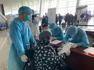 負責登記和處理防疫包的人員與昨日一樣，穿上藍色保護服裝和頭套，並佩戴口罩及防疫膠片。