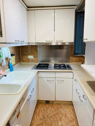 廚房設有多組白色廚櫃，提供充裕收納空間。