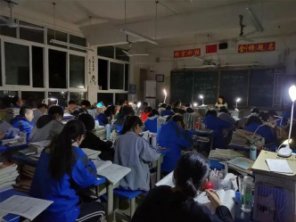四川一所中学学生停电下自备枱灯继续温习。网图