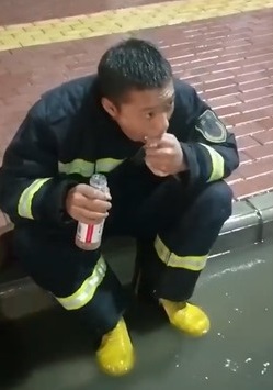 一名消防员因救灾没空吃饭，随意坐在马路上「就地开餐」。　网图