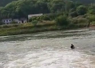 女童墮河後，休班武警何勇進下河救助。影片截圖