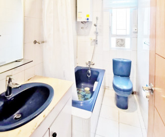 浴室白色装潢，配以蓝色洗手盆、浴缸和座厕。