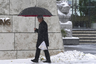 民眾撐着雨傘擋雪。美聯社圖片