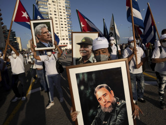 有民众手持党旗、横额，及印有已故革命英雄肖像的标语牌。AP图片