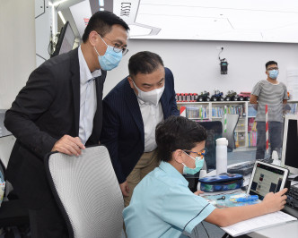 杨润雄（左一）参观电脑室，了解同学上网课的情况。　