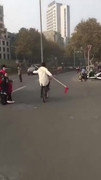 男子踩單車舞紅纓槍。(網圖)