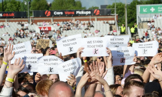 观众高举「We Stand Together」标语字句纸牌。美联社