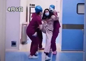 多名护士捉住妇人，阻止她动手。影片截图