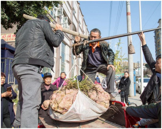 在两名中年男子的协助下才秤出红薯的重量。网图