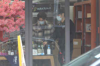 翟威廉（右）向周志文展示櫥窗前的日本清酒。