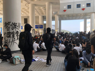 破坏行动结束后，学生们撑伞经吴家玮学术廊走回赛马会大堂坐下。