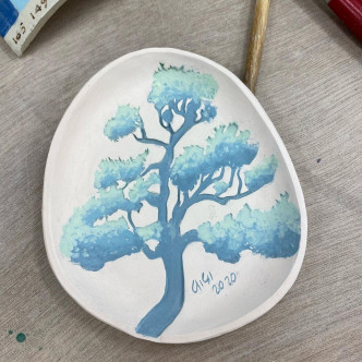 梁詠琪用釉下彩在小碟子繪畫樹木圖案。