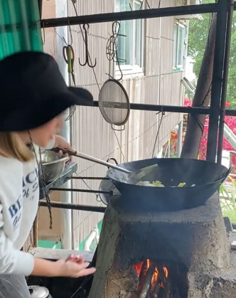 鄭融跟村民學用石爐燒柴炒菜，功架十足。