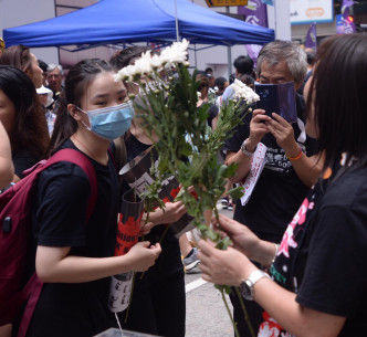 游行市民带同鲜花悼念堕毙的反修例市民。