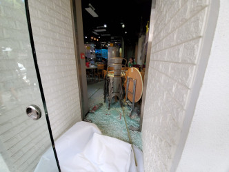 食店其中一隻玻璃門遭扑毀，碎片散落一地。 林思明攝