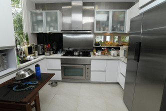  廚房採梗廚設計，設有多組廚櫃及吊櫃，備有焗爐等家電。
