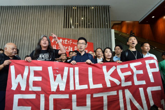 他们拉著写有「WE WILL KEEP FIGHTING」横额离开立法会。郭显熙摄
