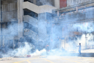 防暴警員衝出，在筲箕灣道舉黑旗和發射催淚彈。