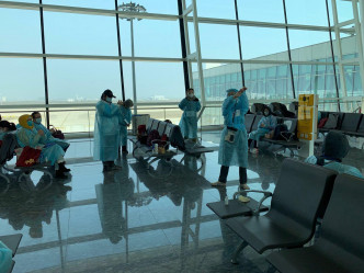 衛生署職員在登機閘口教導港人穿保護衣物及清潔雙手。