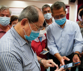 陈茂波（右）昨日出席社区活动，了解长者使用手机和电子钱包的情况。网图