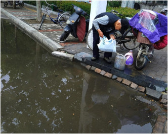 用胶袋收集路边的积水再倒入胶桶内。